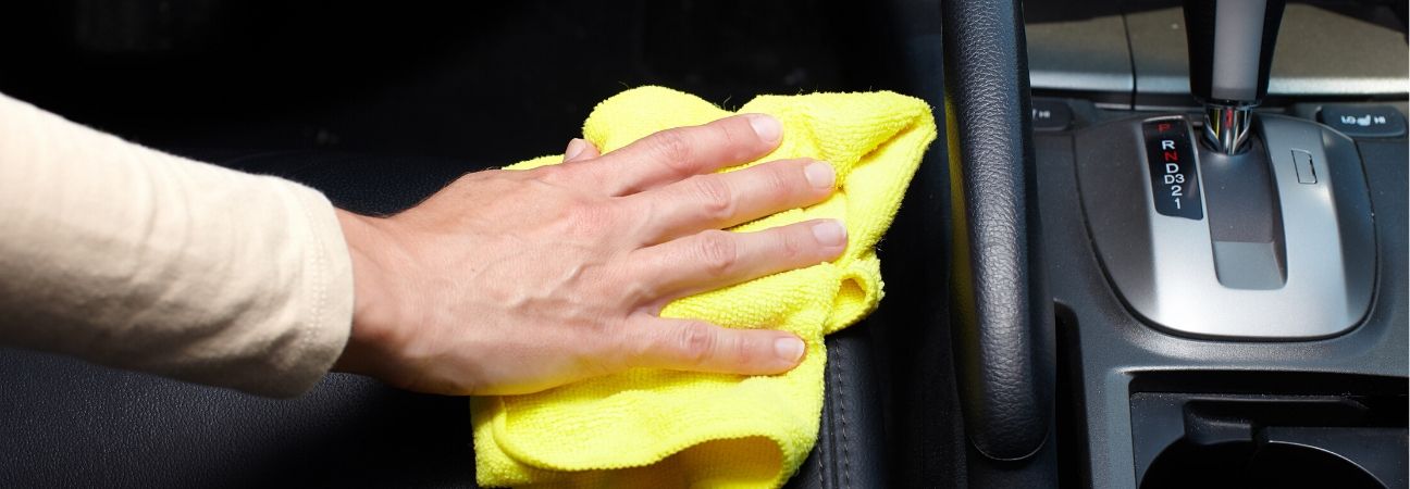 hand cleaning leather seats with yellow terry cloth